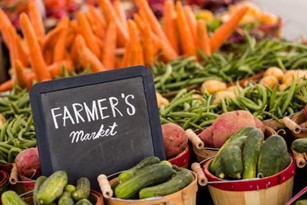 Farmers' Market sign surrounded by baskets of fresh produce