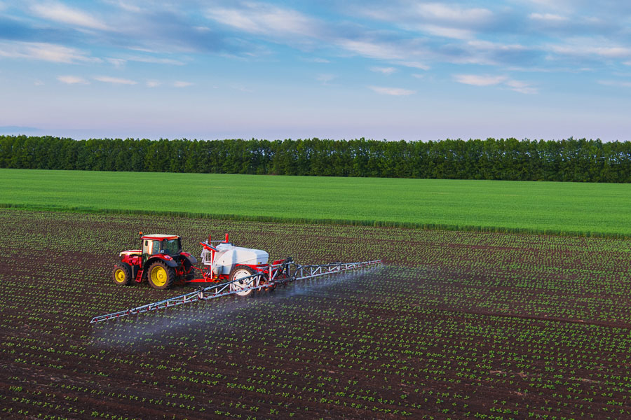 farmer in tractor spraying fields in spring