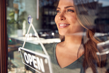 A person standing by a window with an open sign