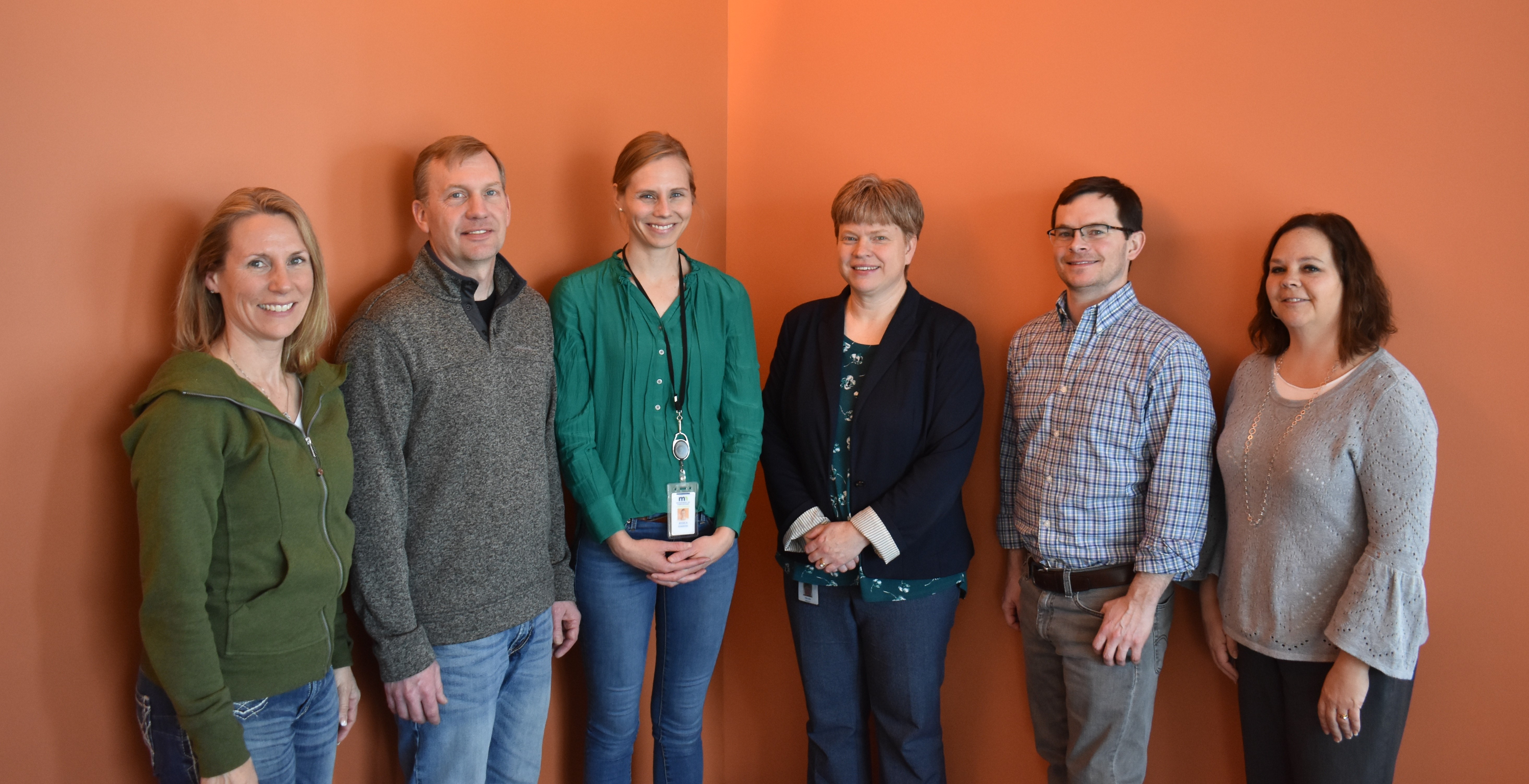 Six people stand in a row, posing for a photograph.