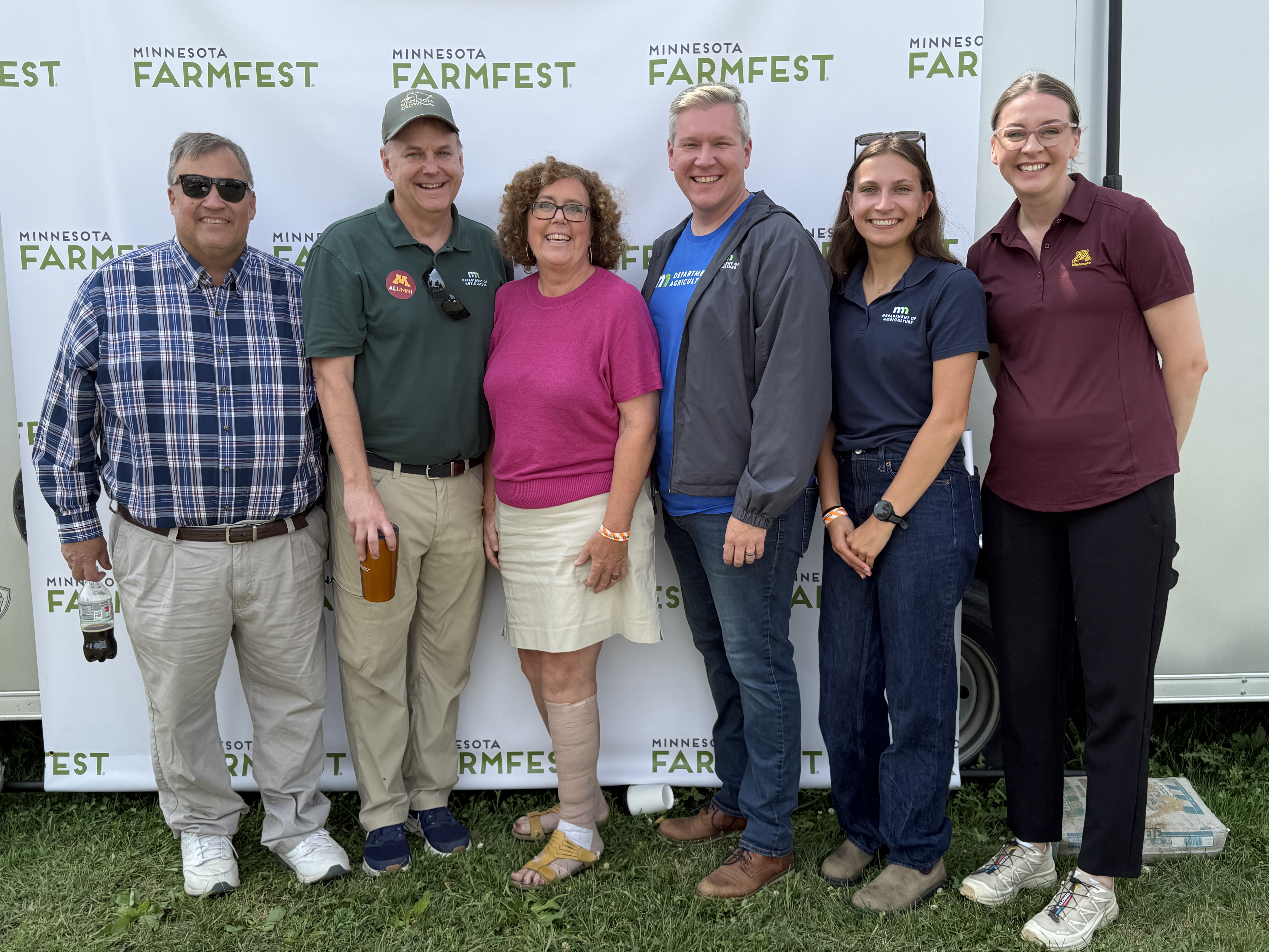 Six people stand in front of a Minnesota Farmfest backdrop after Meg Moynihan was named the 2026 Farmfest Woman Farmer of the Year.