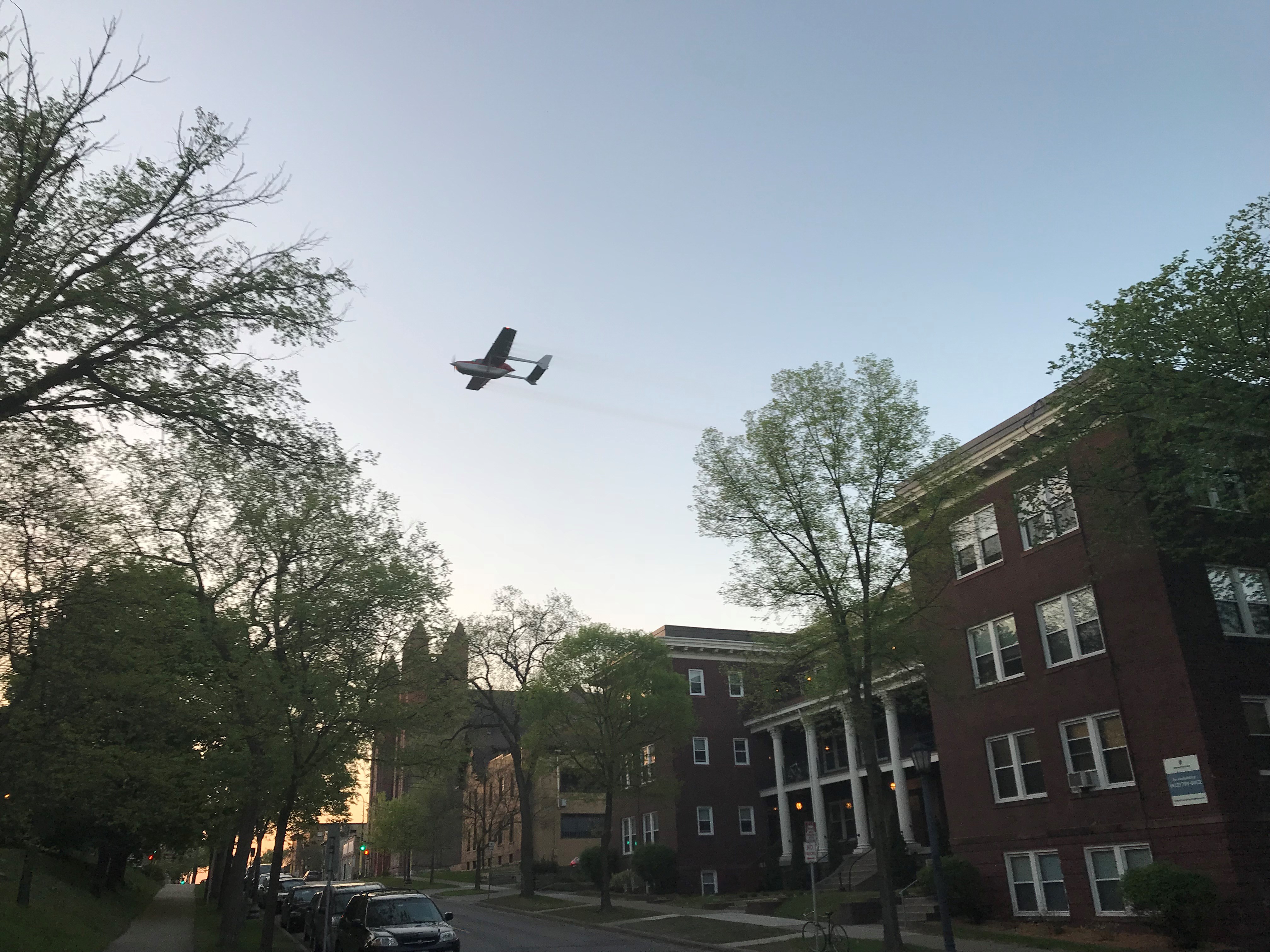 A plane conducts a gypsy moth treatment in an urban area