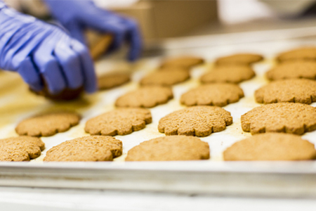 gloved hands picking up cookies from tray