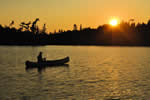 Person fishing in a canoe at sunset