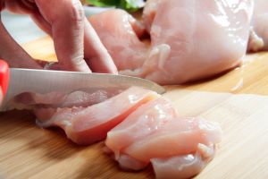 cutting raw chicken on cutting board