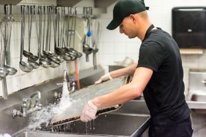 A food worker washing a pan in a sink