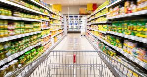 A cart being pushed through a grocery store aisle.