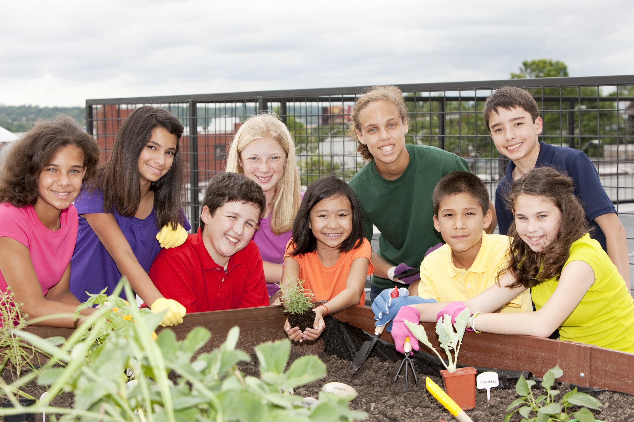 Group of ethnically diverse kids planting an urban rooftop garden