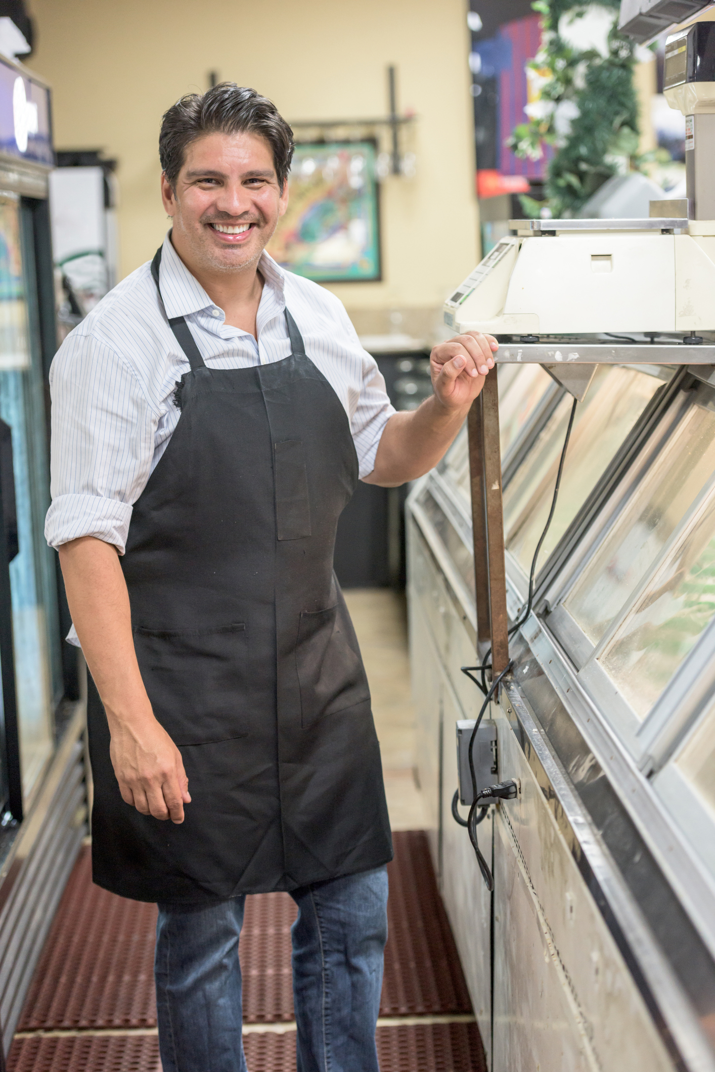 Small business owner standing next to meat cooler