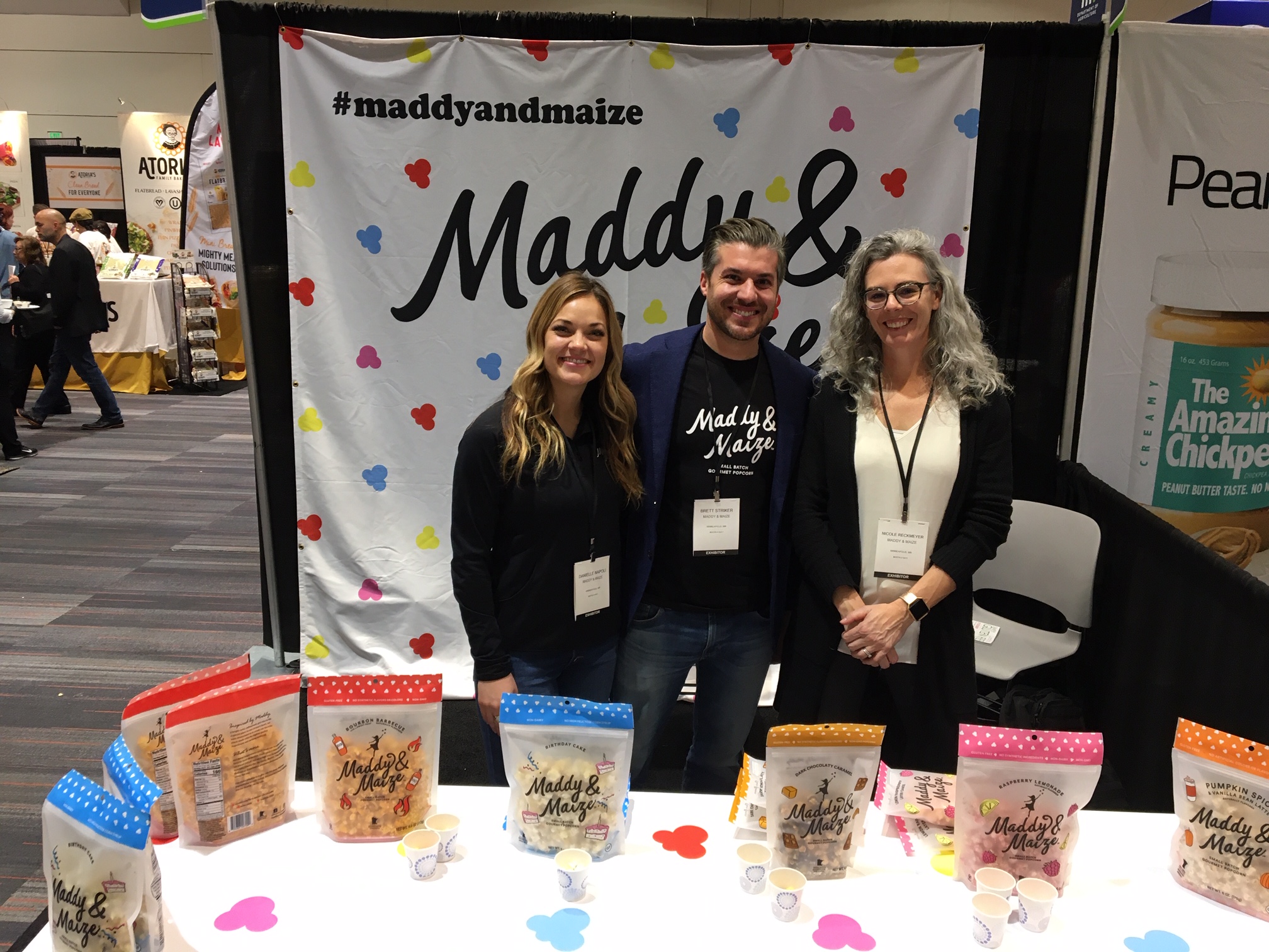three people standing by their products in a trade show booth