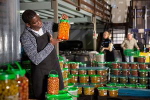 Man in food warehouse holding a jar of food and standing among other jars