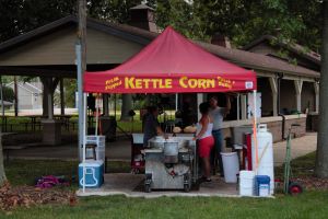 •	Kettle corn seasonal temporary stand with red tent and people preparing food