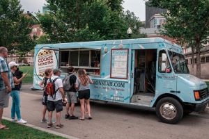 People buying cookie treats from a blue cookie mobile food truck 