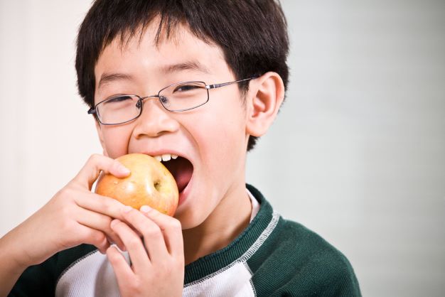 boy with glasses biting into an apple
