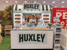 Three smiling staff holding CPG beverages in front of a tradeshow display